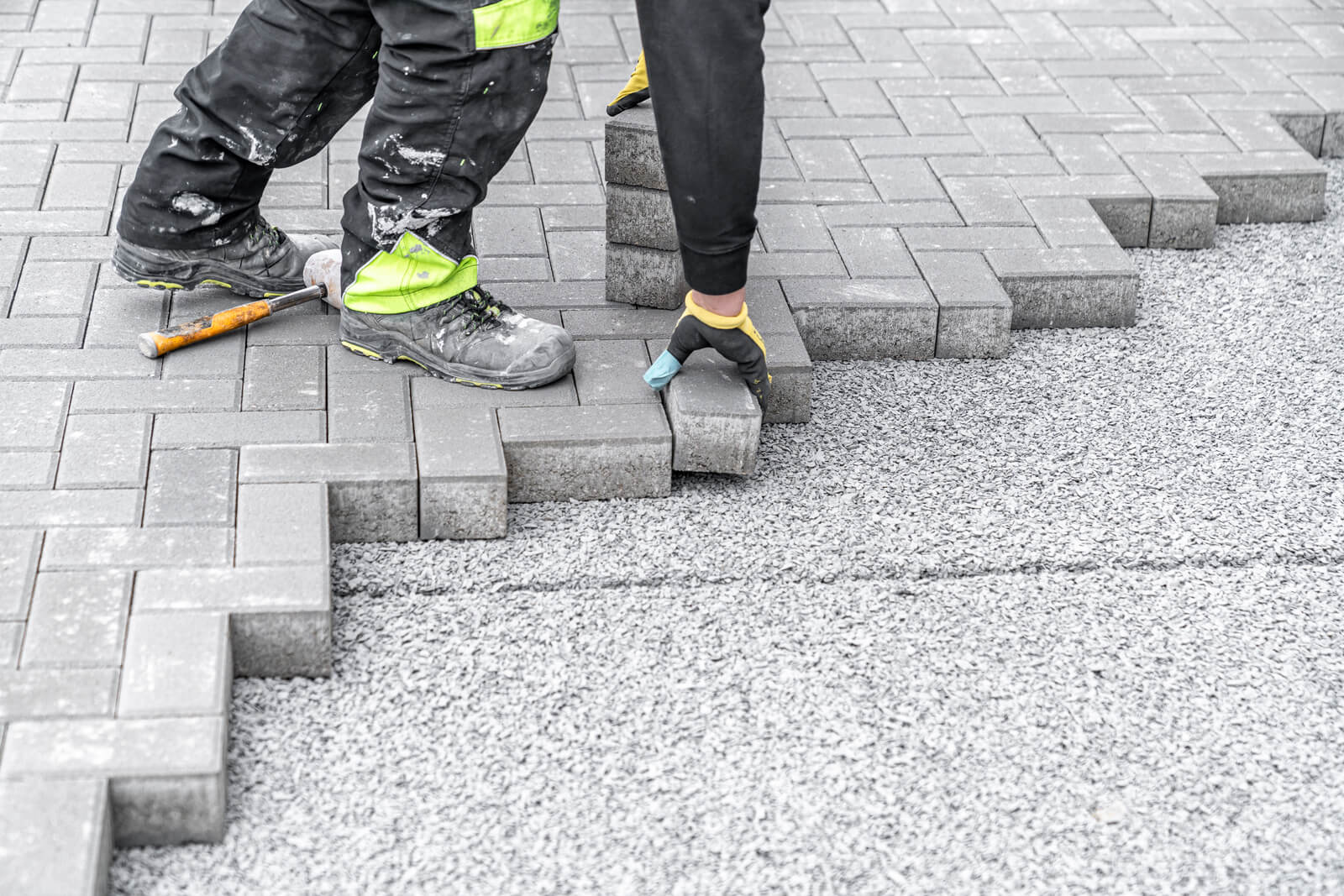 Driveway installation process showing professional paver laying and site preparation